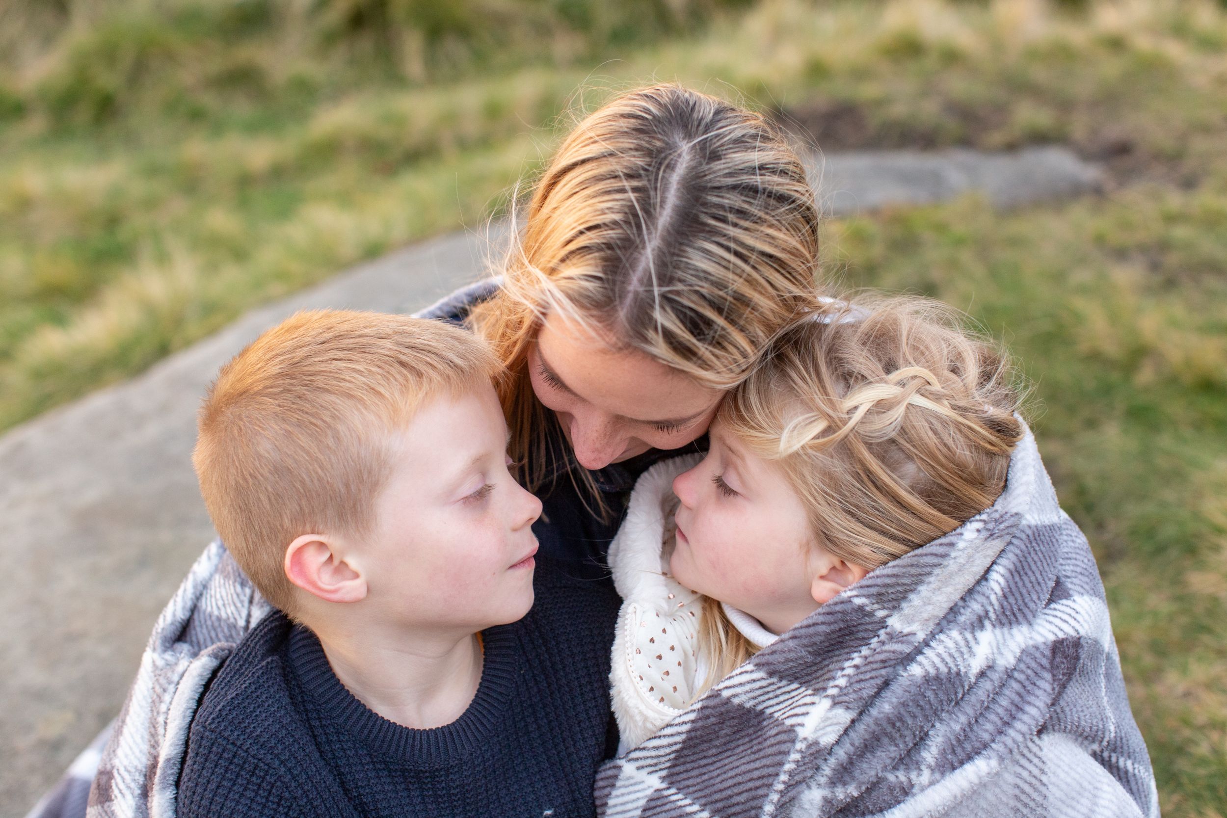 Intimate family moment shared outdoors wrapped in cozy sweaters.