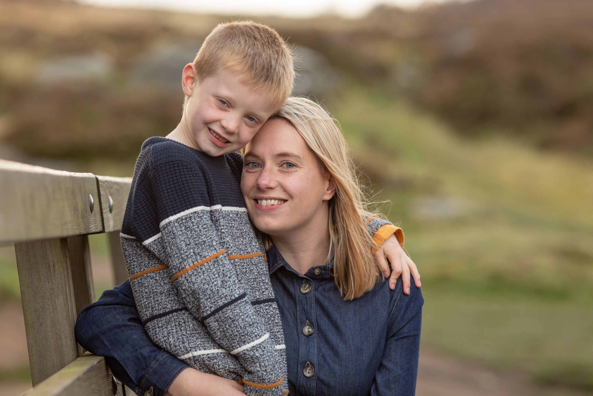 A casual outdoor portrait showing warm bonding moment on a wooden bench in nature.