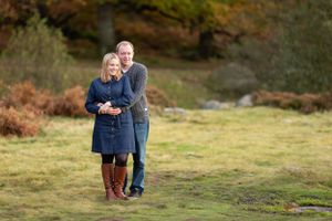 Couple sharing an intimate embrace while standing in an autumn field.