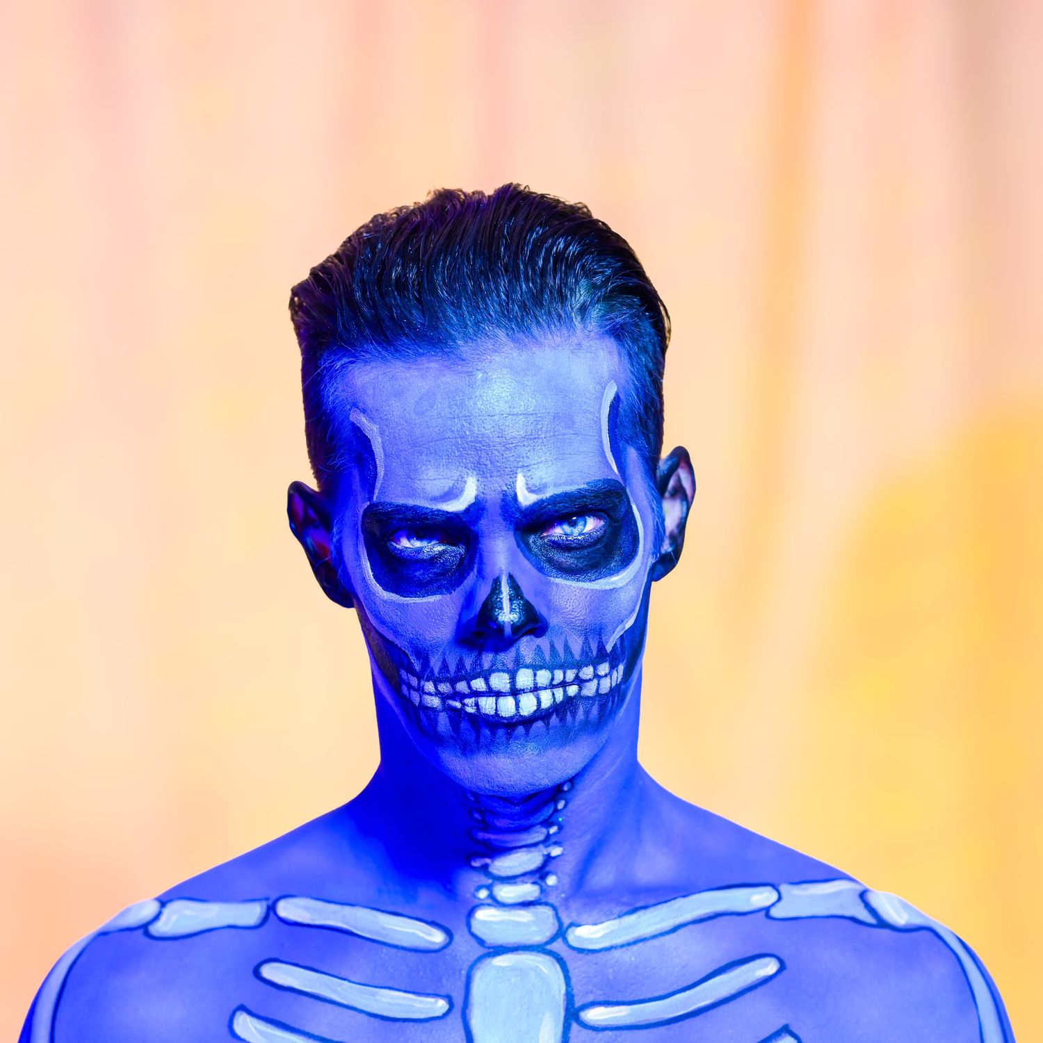 Eerie blue-lit portrait featuring skull-inspired face paint and dark shadows.