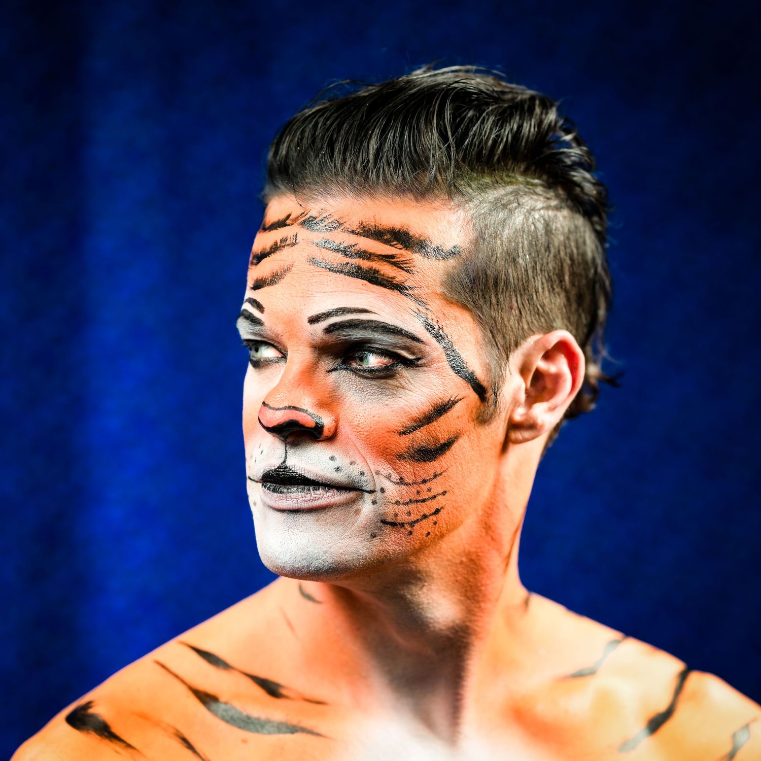 Artistic tiger face paint makeup design against dark blue background in sequential shots.
