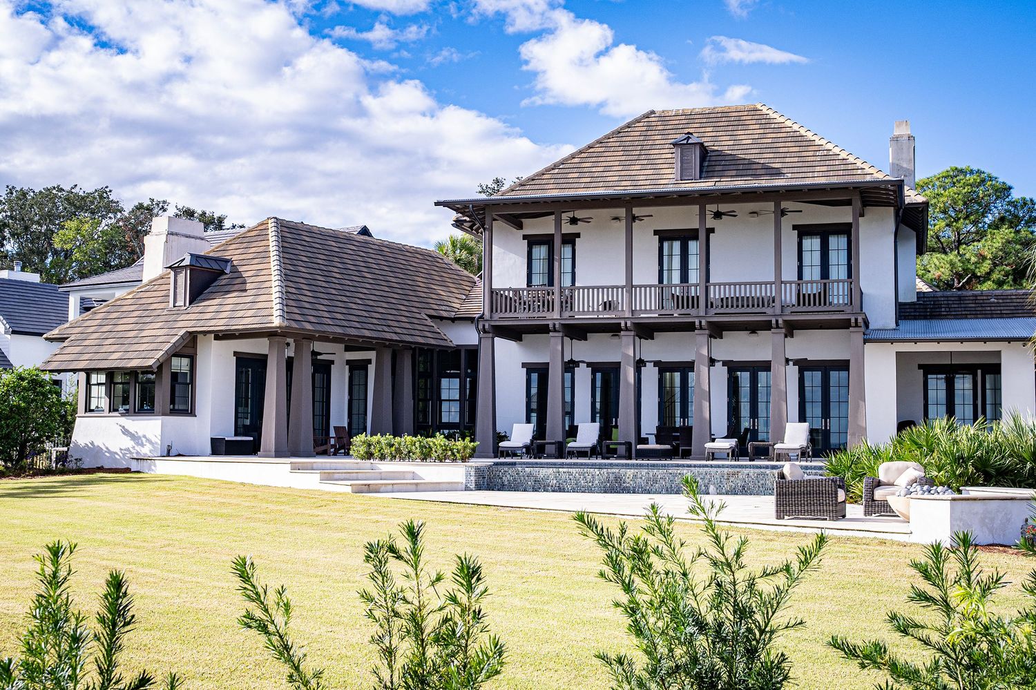 A modern single-story home exterior with a sloping roof against a blue sky and wispy clouds.