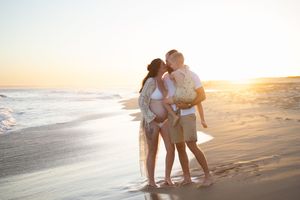 Newcastle maternity photographer capturing mother-to-be with husband and toddler at beach at golden hour