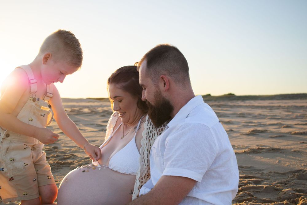 Newcastle maternity photographer capturing mother-to-be with husband and toddler at beach