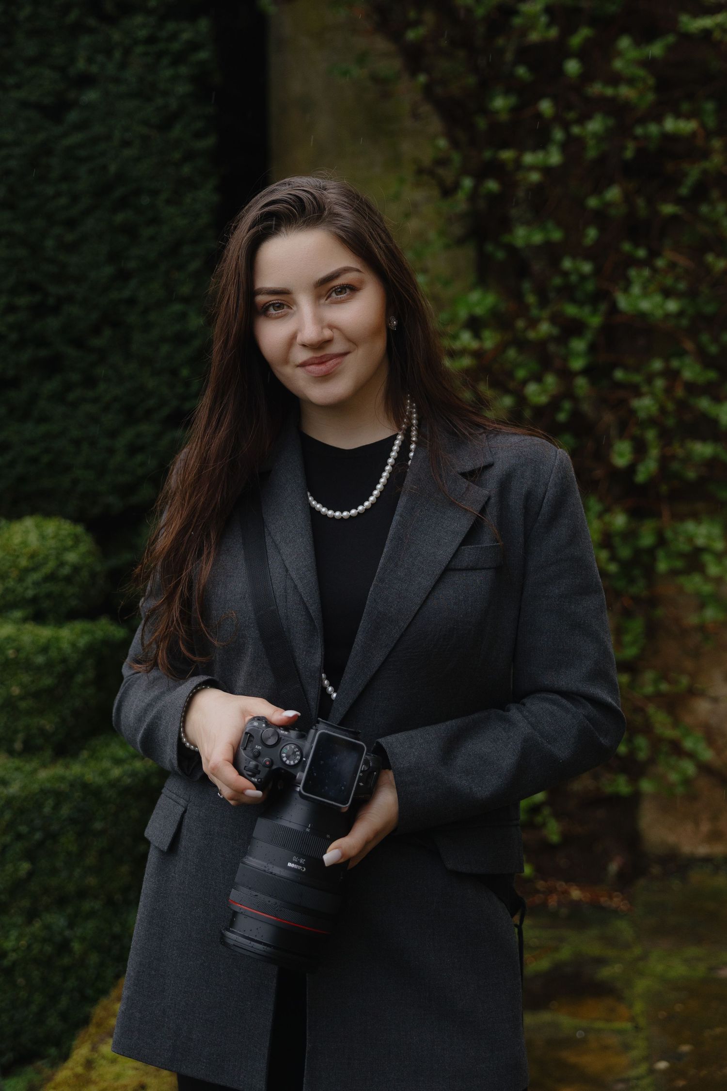 A woman in a black sweater and patterned scarf poses against an urban backdrop in a series of connected photos.