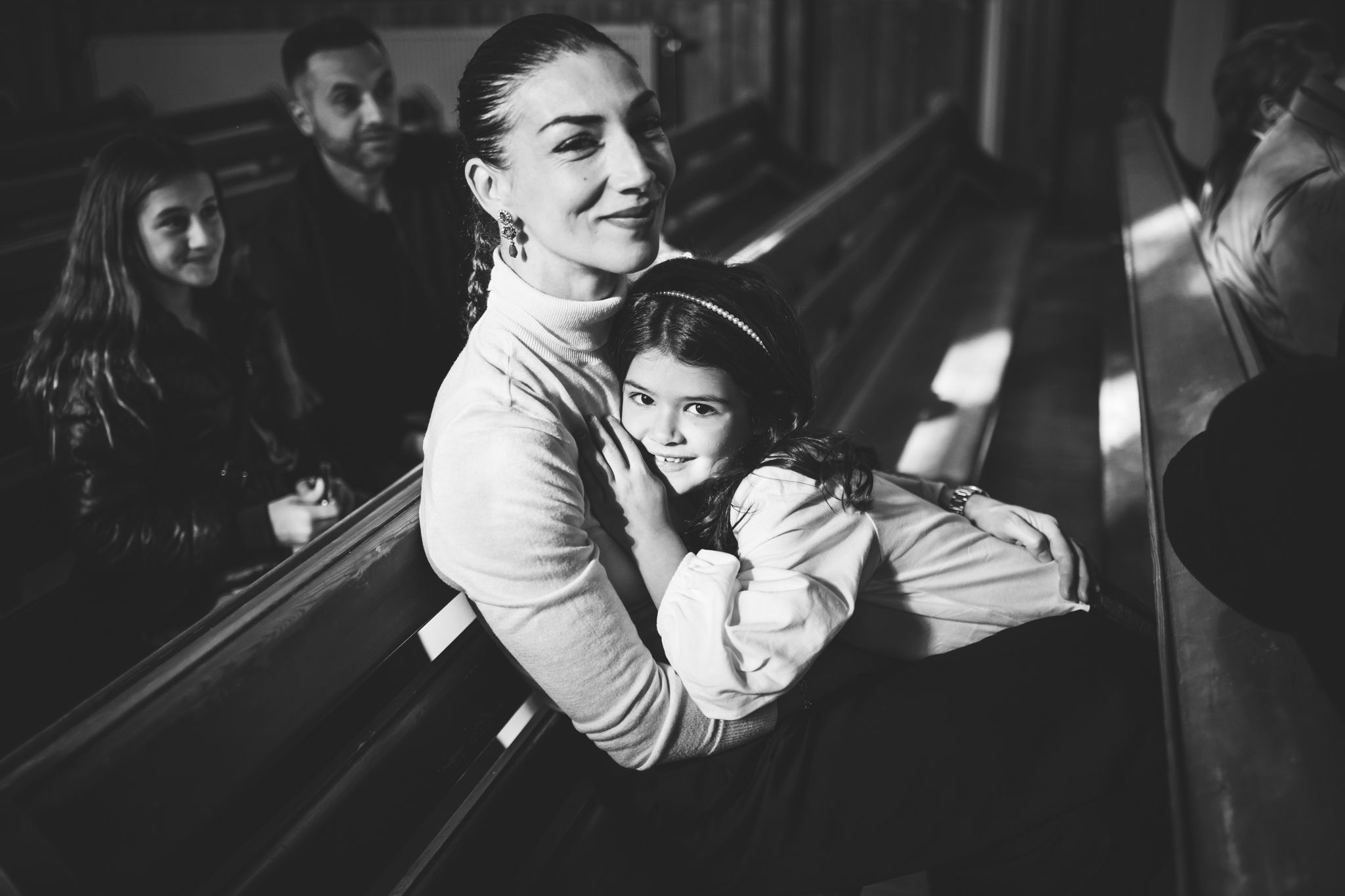 A black and white photograph shows a person dancing with a child in a dimly lit space during a social gathering.