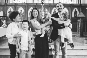 Black and white photograph of a family group gathered inside a church with ornate wooden paneling in the background.