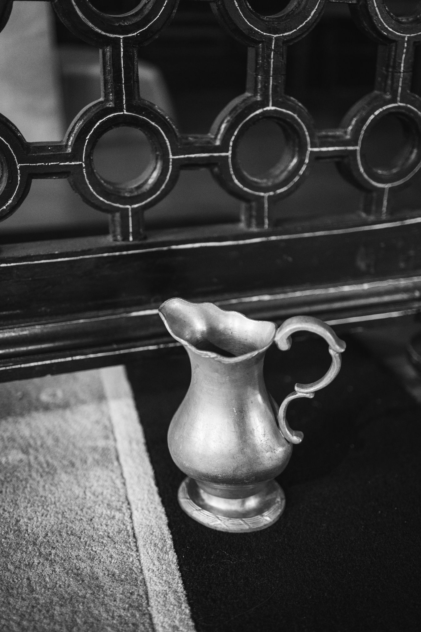 Black and white close-up of ornate wrought iron railing details with decorative curves and metalwork patterns.