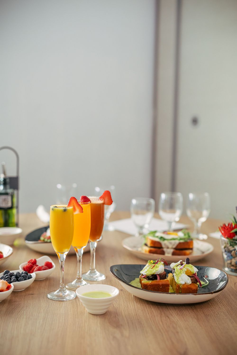 Elegant table setting with wine glasses and appetizer plates arranged in a row on a wooden surface.