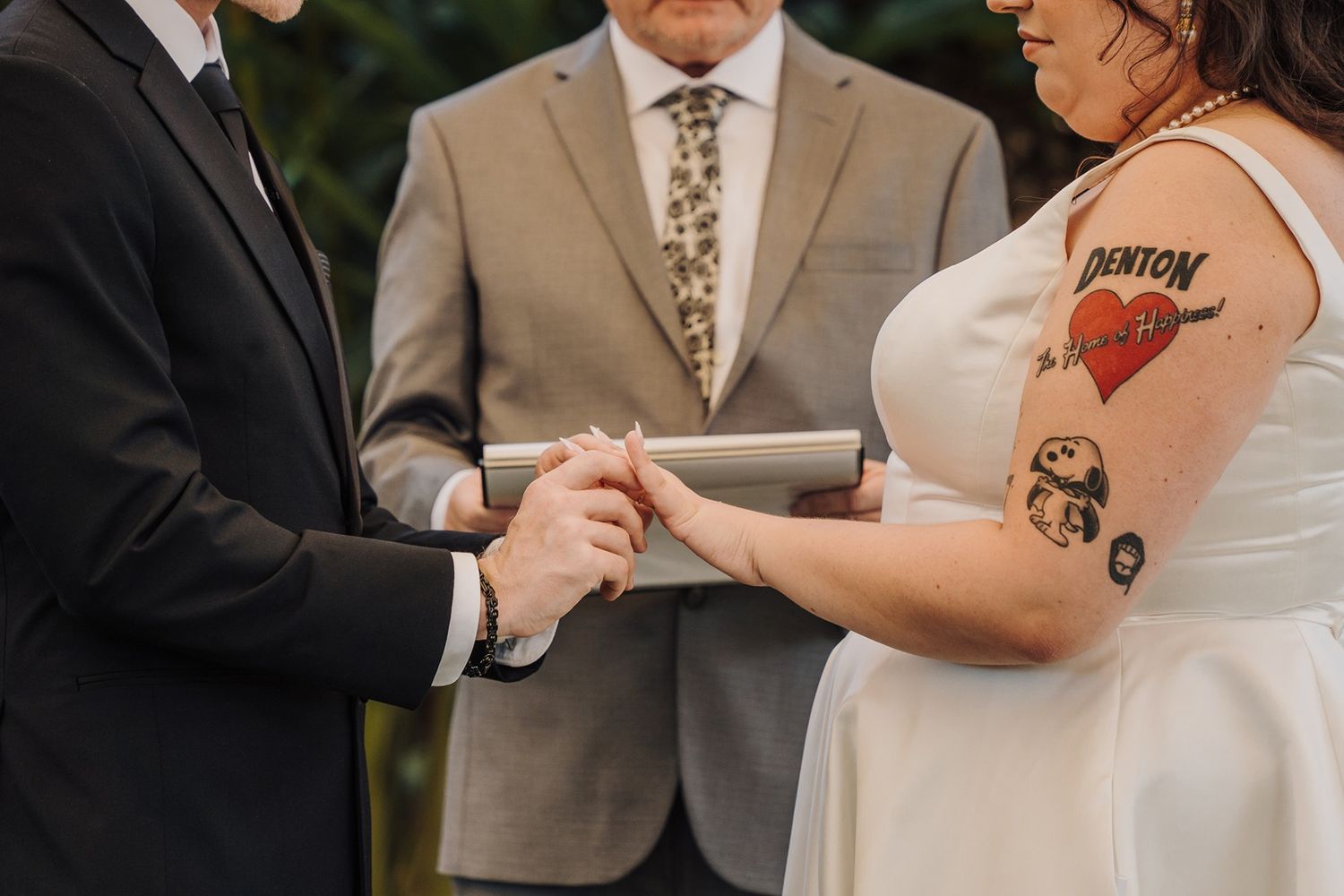 A couple exchanges rings during an outdoor wedding ceremony in a romantic garden setting at River Garden Weddings and Events..