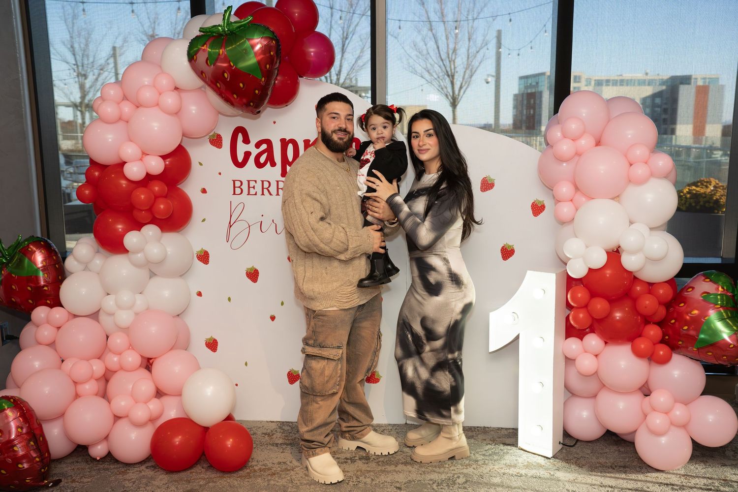 Pink and red balloon arches decorate a Valentine's Day themed event space with festive decorations and displays.
