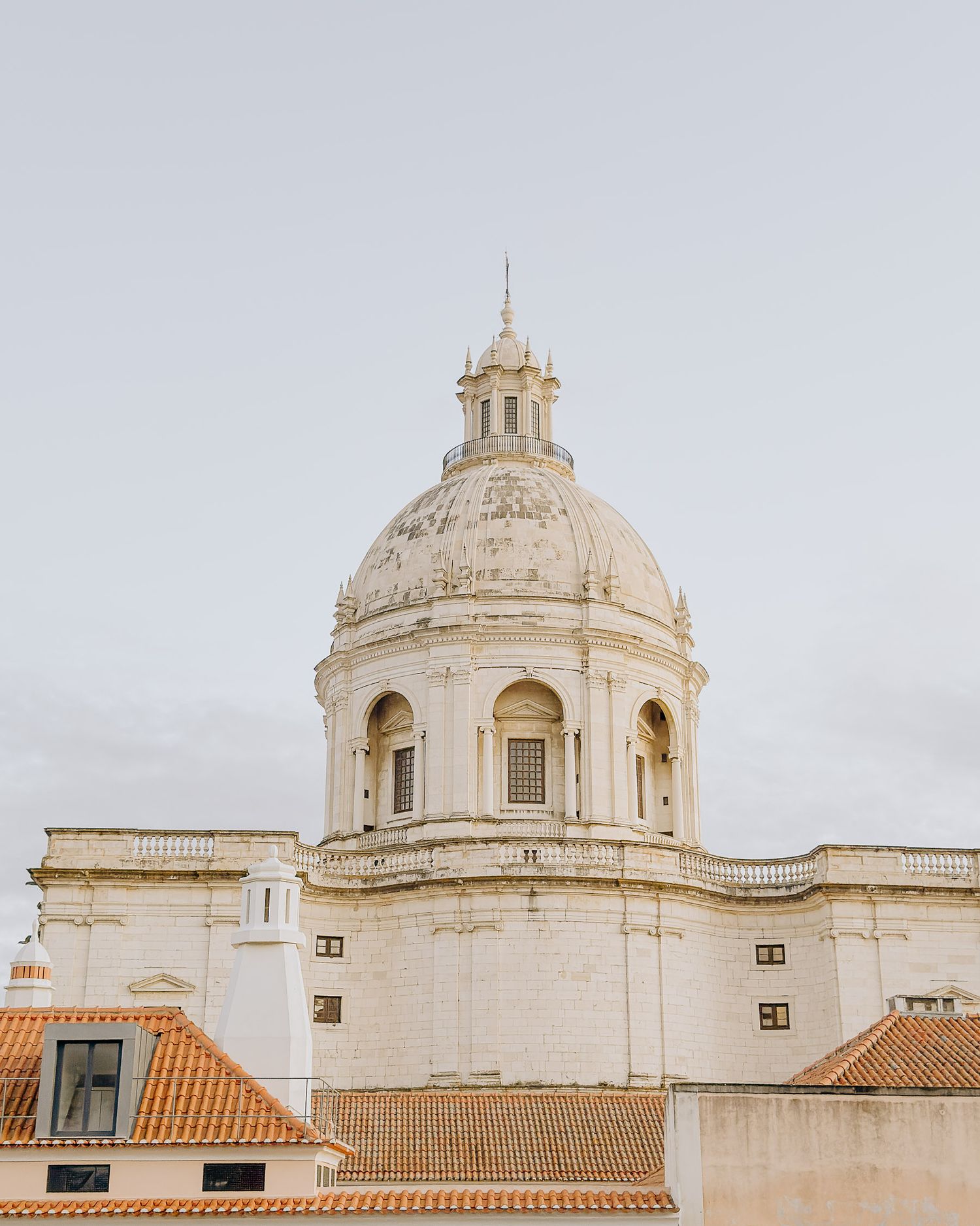 White baroque domes and architectural details against a pale sky in Portugal.
