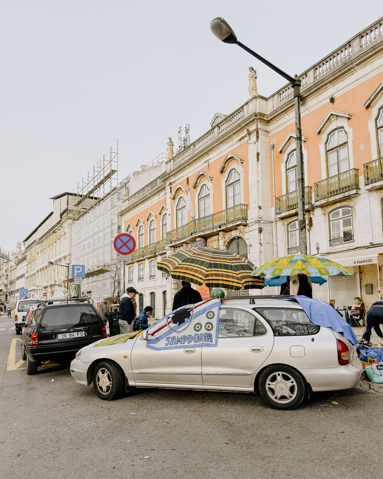 Classic cars parked along a historic European street with traditional architecture and cobblestone pavement.