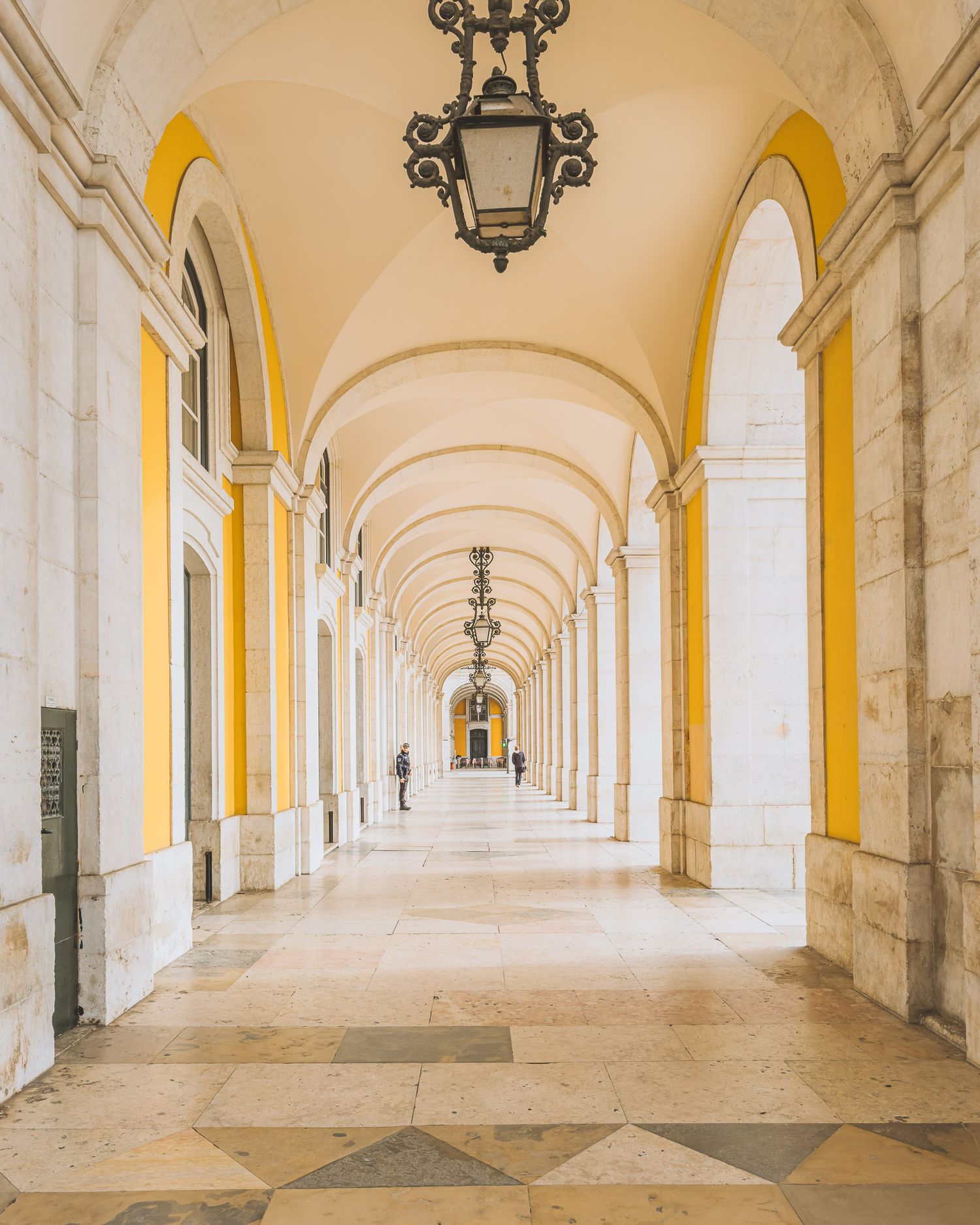 Elegant arched colonnade with yellow and white walls stretching into the distance. Lisbon.