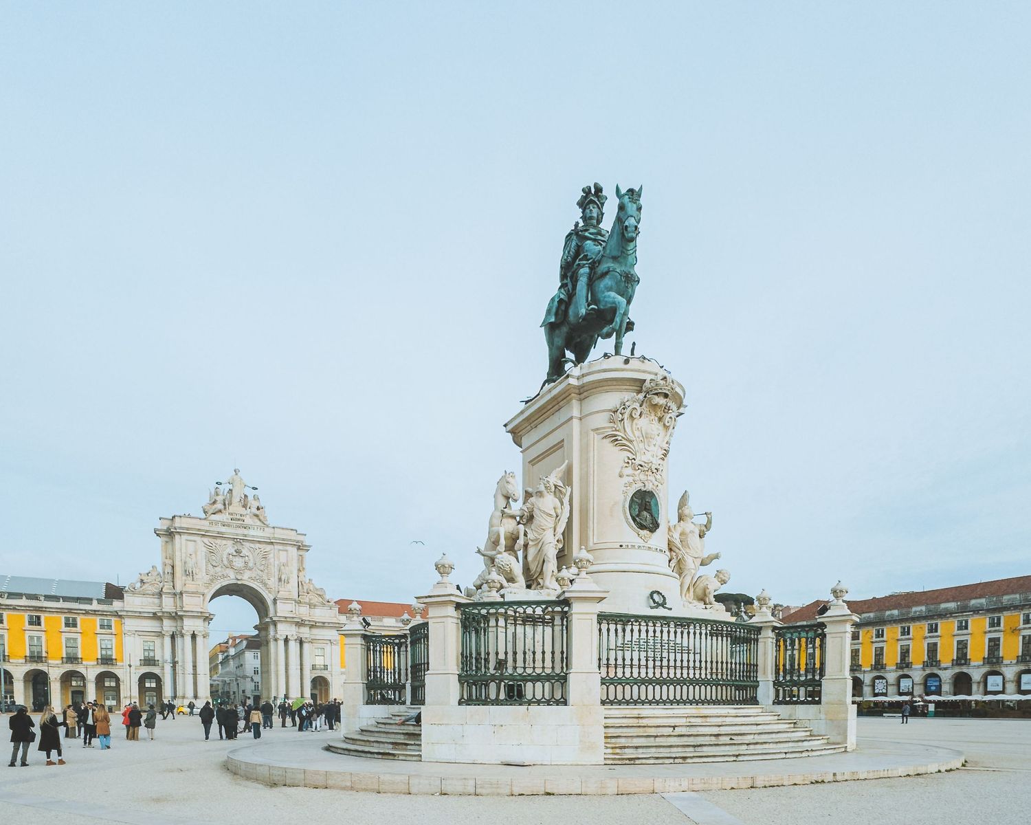 Panoramic view of a grand plaza with equestrian statue and classical architecture in Lisbon.
