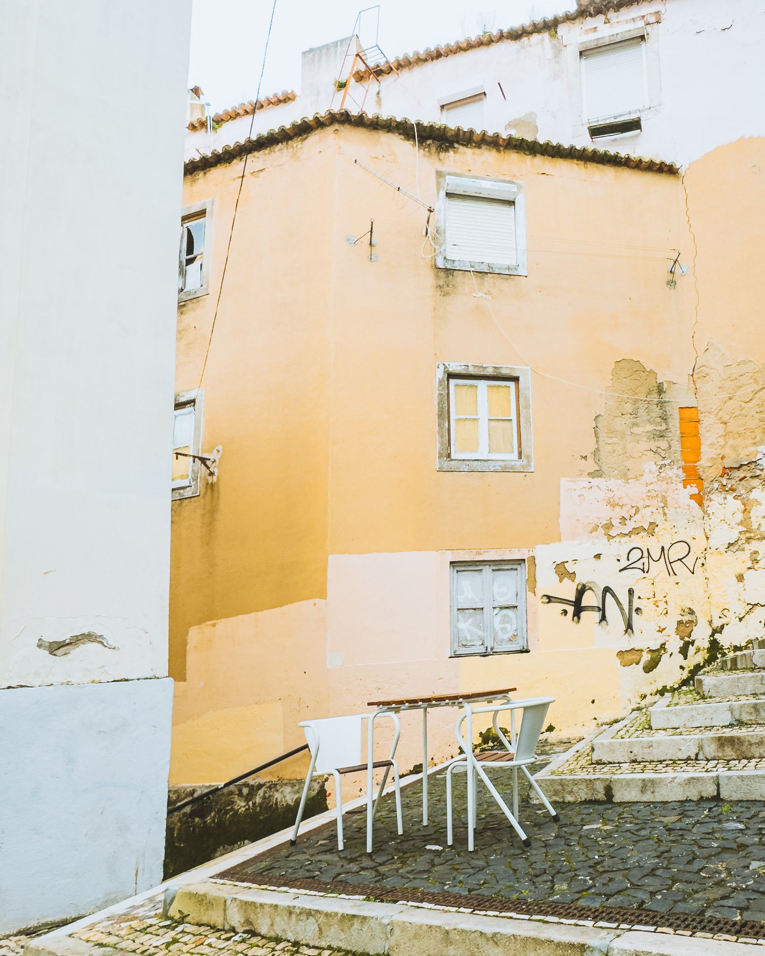 Pastel yellow buildings with white trim and windows on a hillside street.