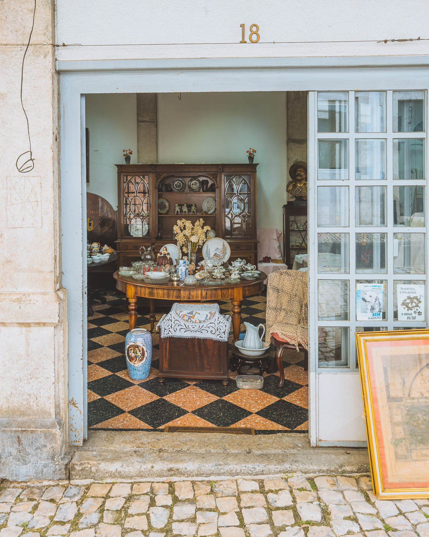 Vintage antique shop window display with decorative plates and ceramics on wooden shelves.