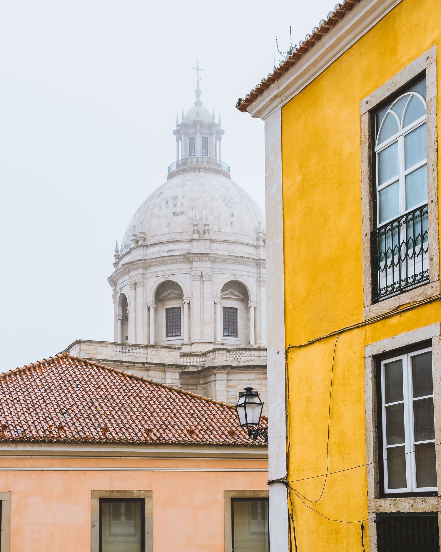 Yellow and pink buildings with white church dome against blue sky in historic district.
