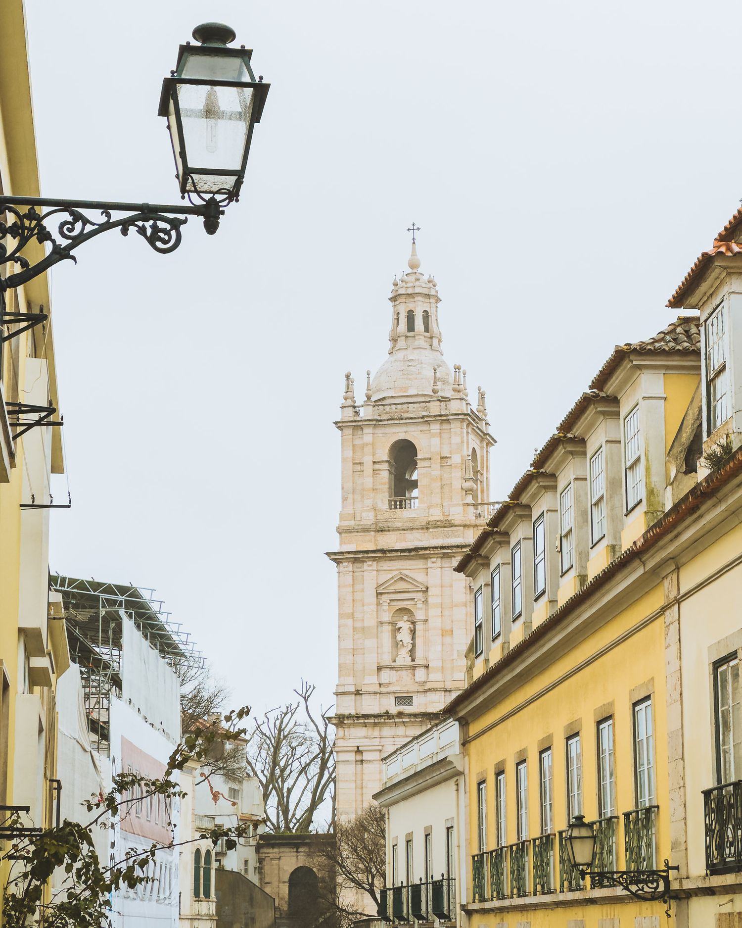 Historic church spires and yellow buildings along narrow street with traditional lanterns.