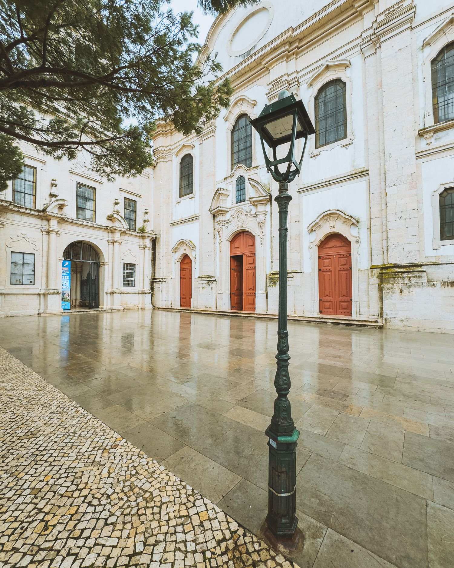 White stone courtyard with red doors and ornate architectural details in classical style.