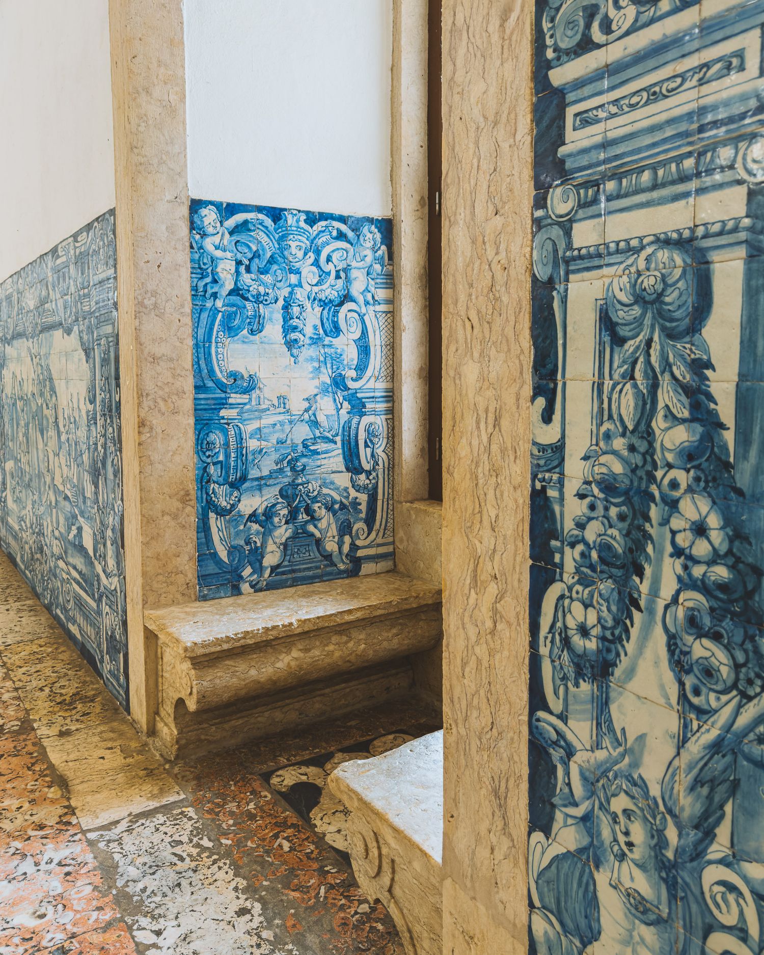 Historic blue and white Portuguese azulejo tiles decorating a corridor wall with intricate patterns and scenes.