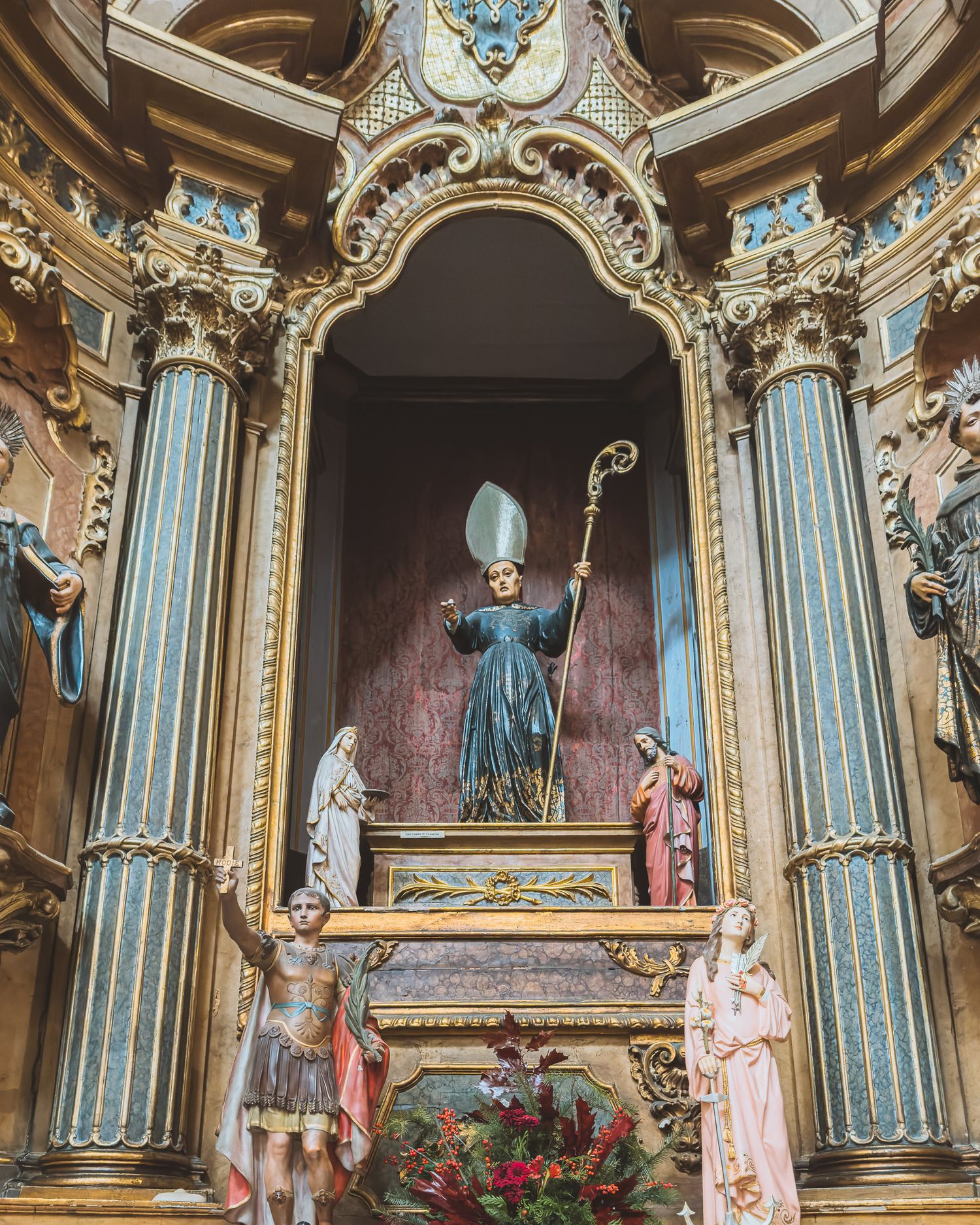 Ornate baroque altar with blue and gold columns featuring religious statues and decorative elements.