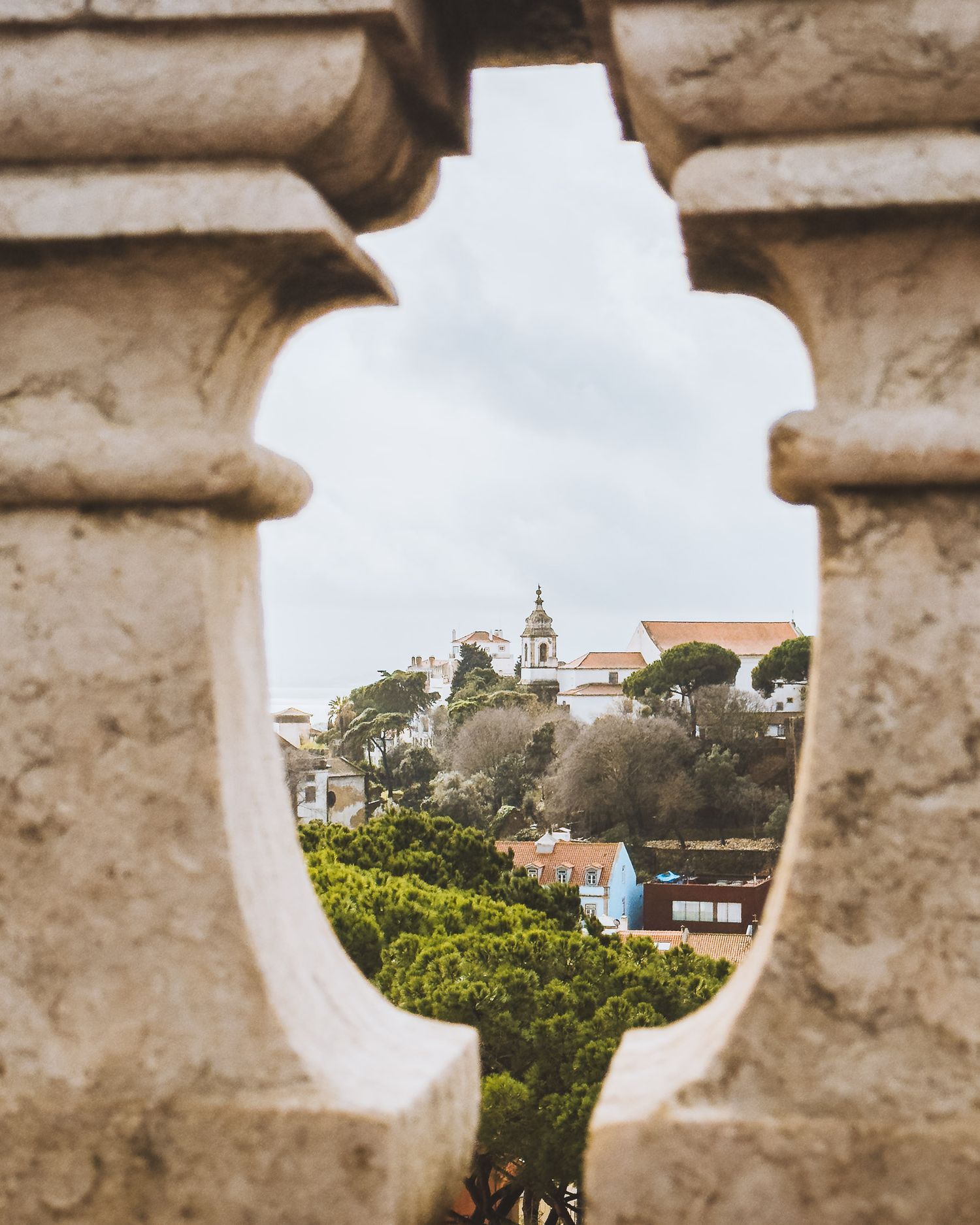 Stone architectural details framing a view of hillside buildings and greenery.