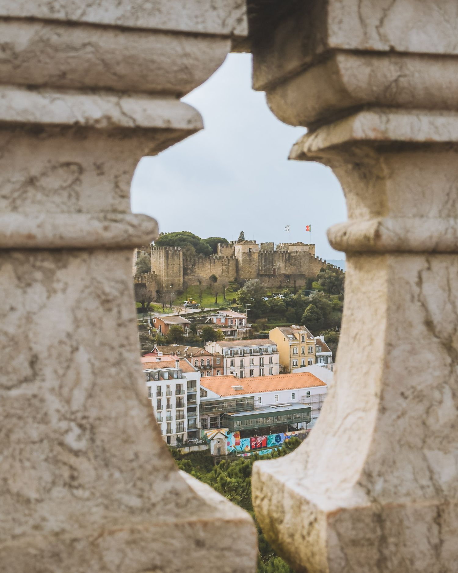 View of historic Lisbon castle and buildings through decorative stone balustrade.