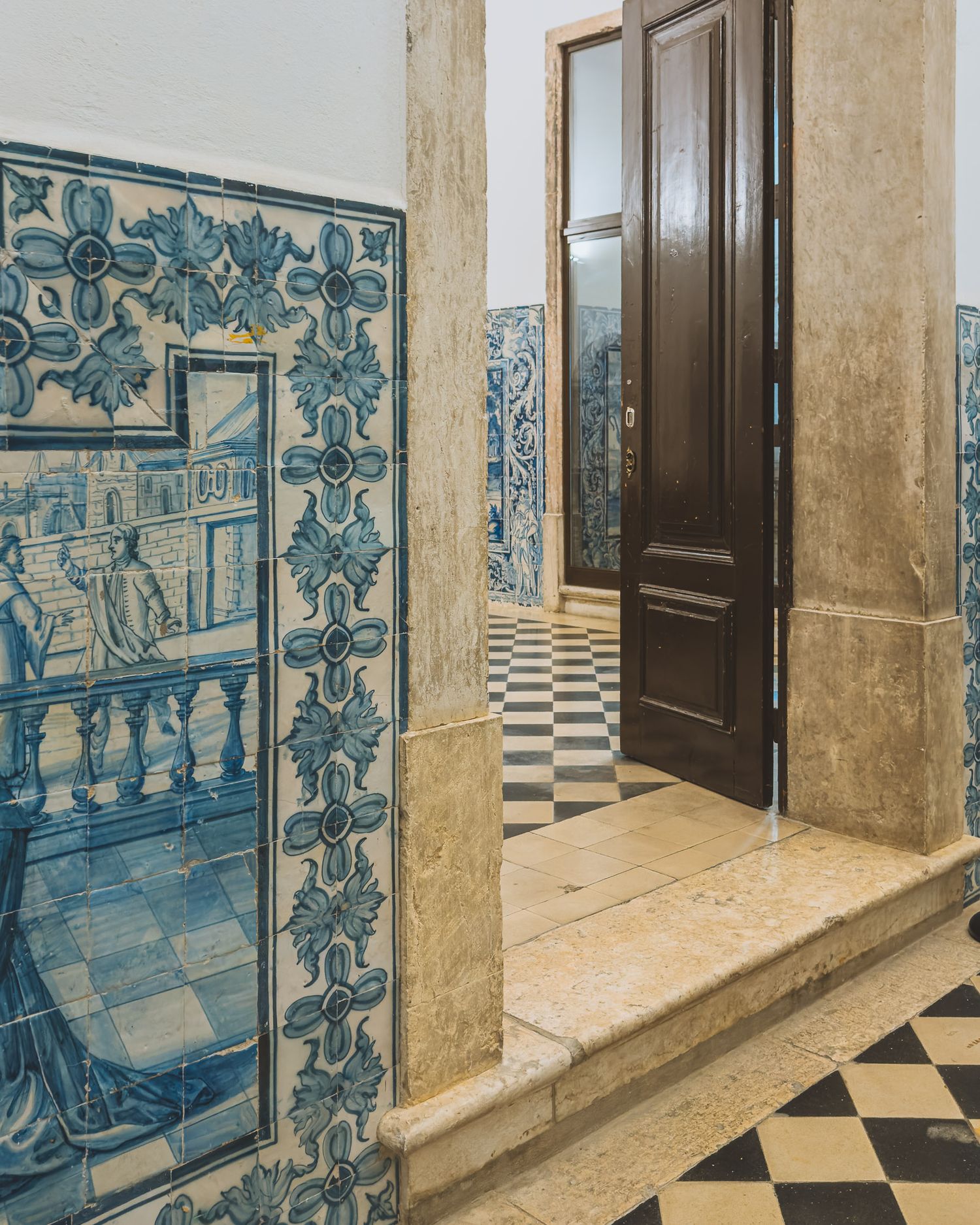 Traditional Portuguese blue and white azulejo tiles decorating a corridor with checkered floor.