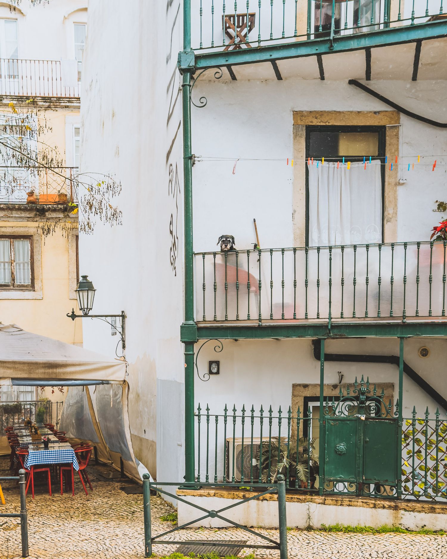 White apartment building exterior with green railings and traditional Mediterranean architecture.