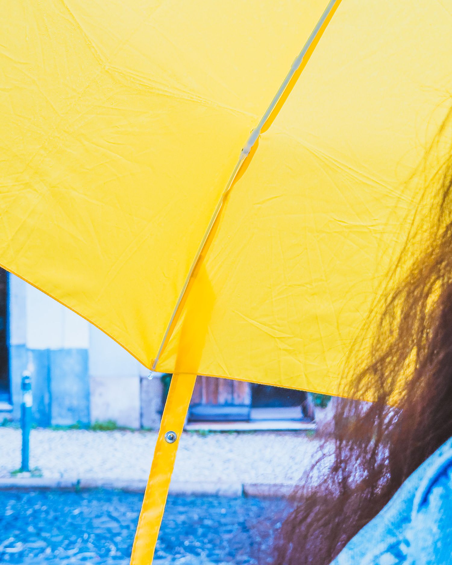 Yellow umbrella against a bright sunny sky creating an abstract minimalist composition.