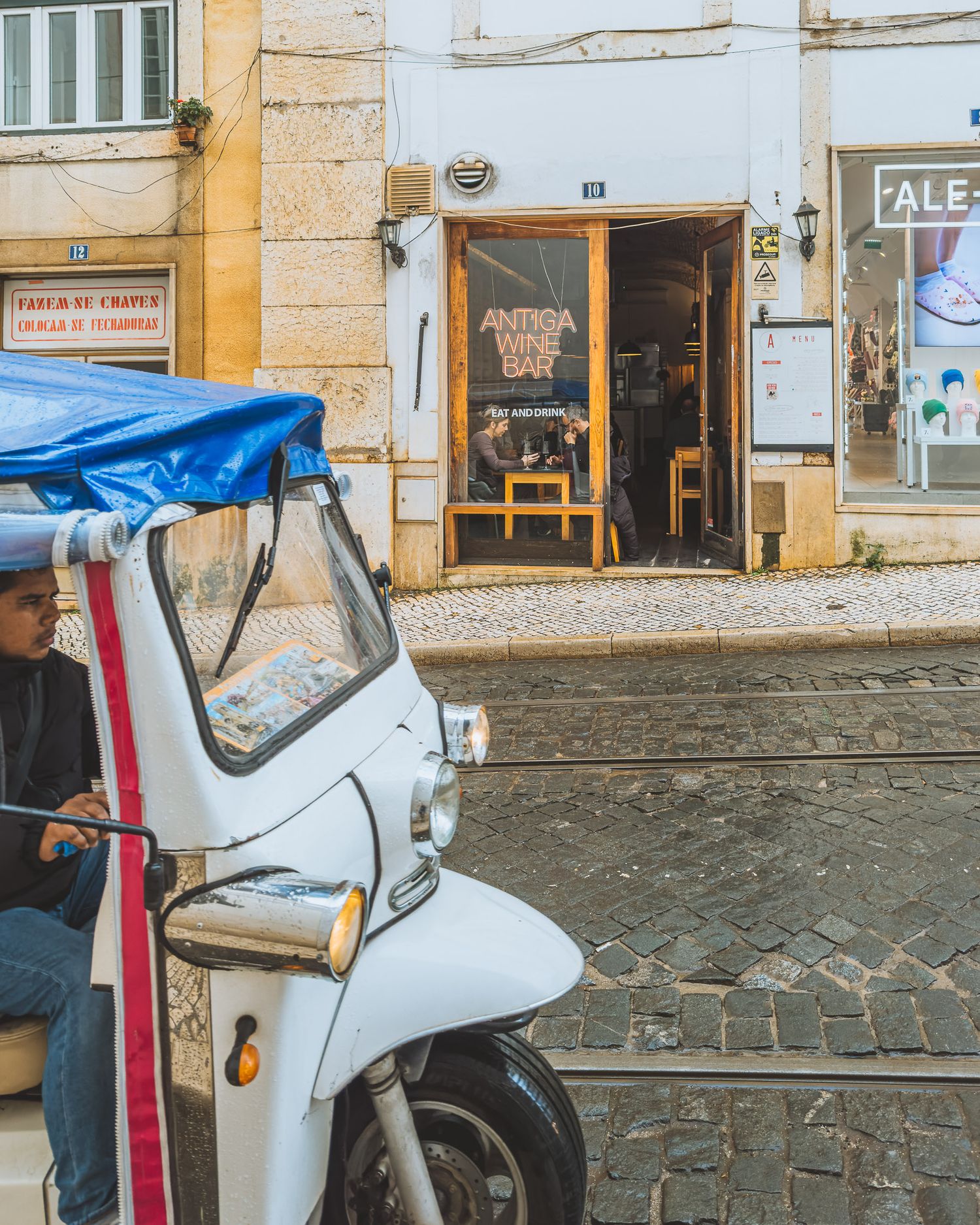 White scooter parked on cobblestone street in front of yellow building facades.