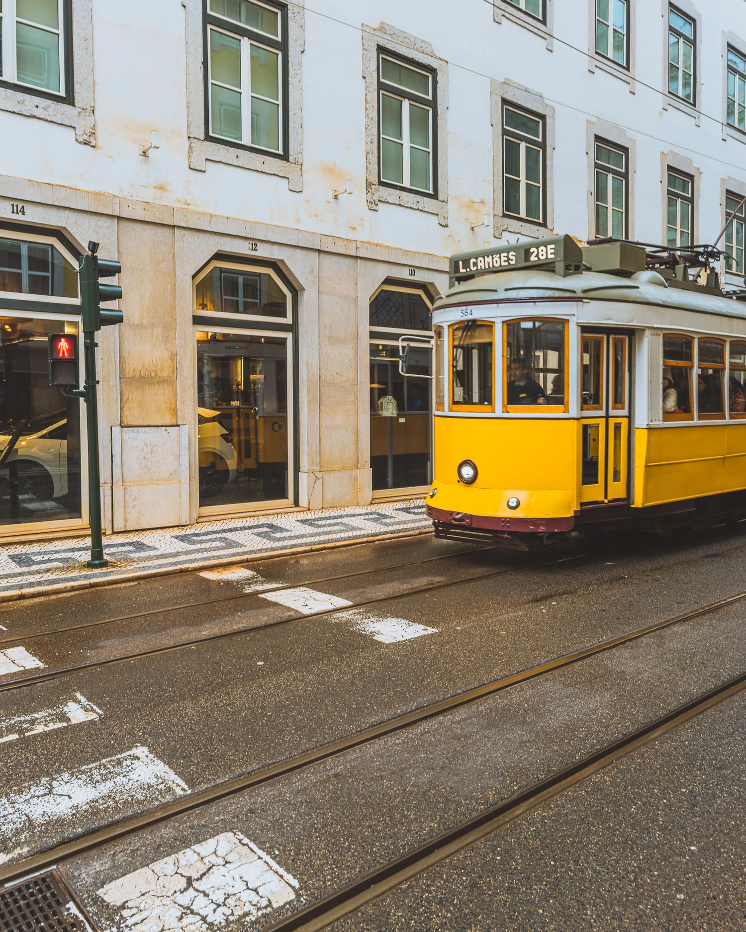 Yellow vintage trams lined up on cobblestone tracks along a historic building facade.