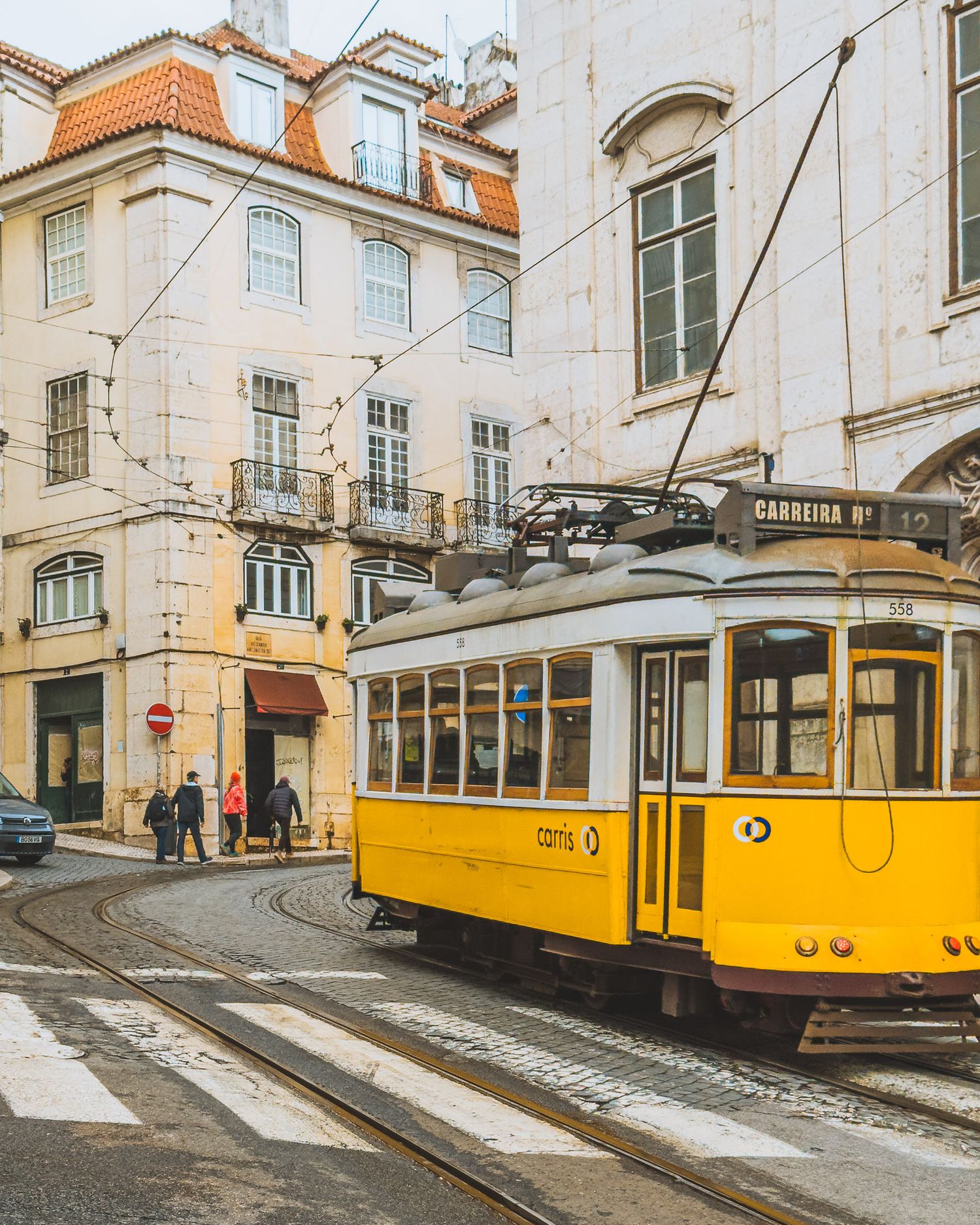 Classic yellow Lisbon trams running along a historic street with traditional architecture.