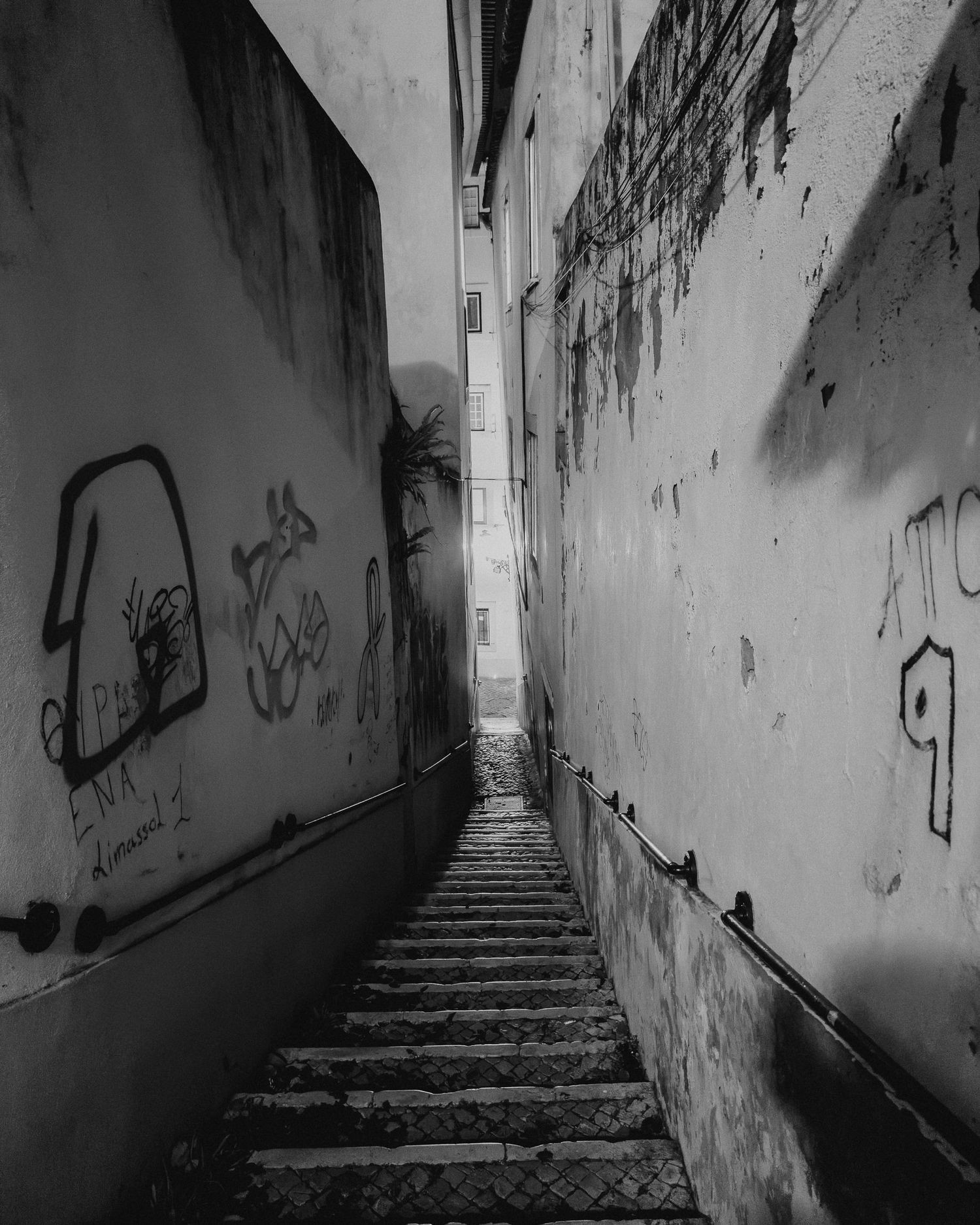 Steep stone steps leading through a narrow passage with graffiti-covered walls.