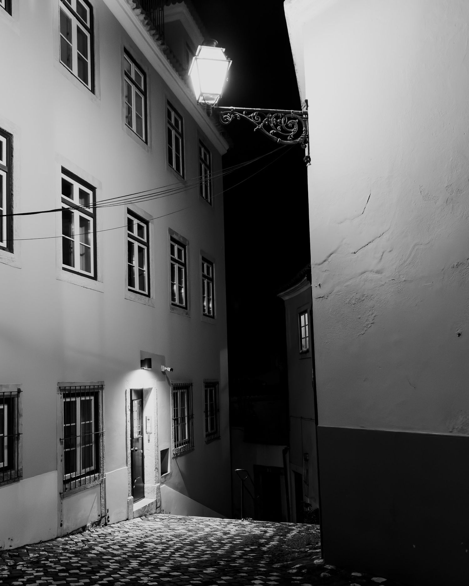 Historic building facade with illuminated windows and street lamps at night.