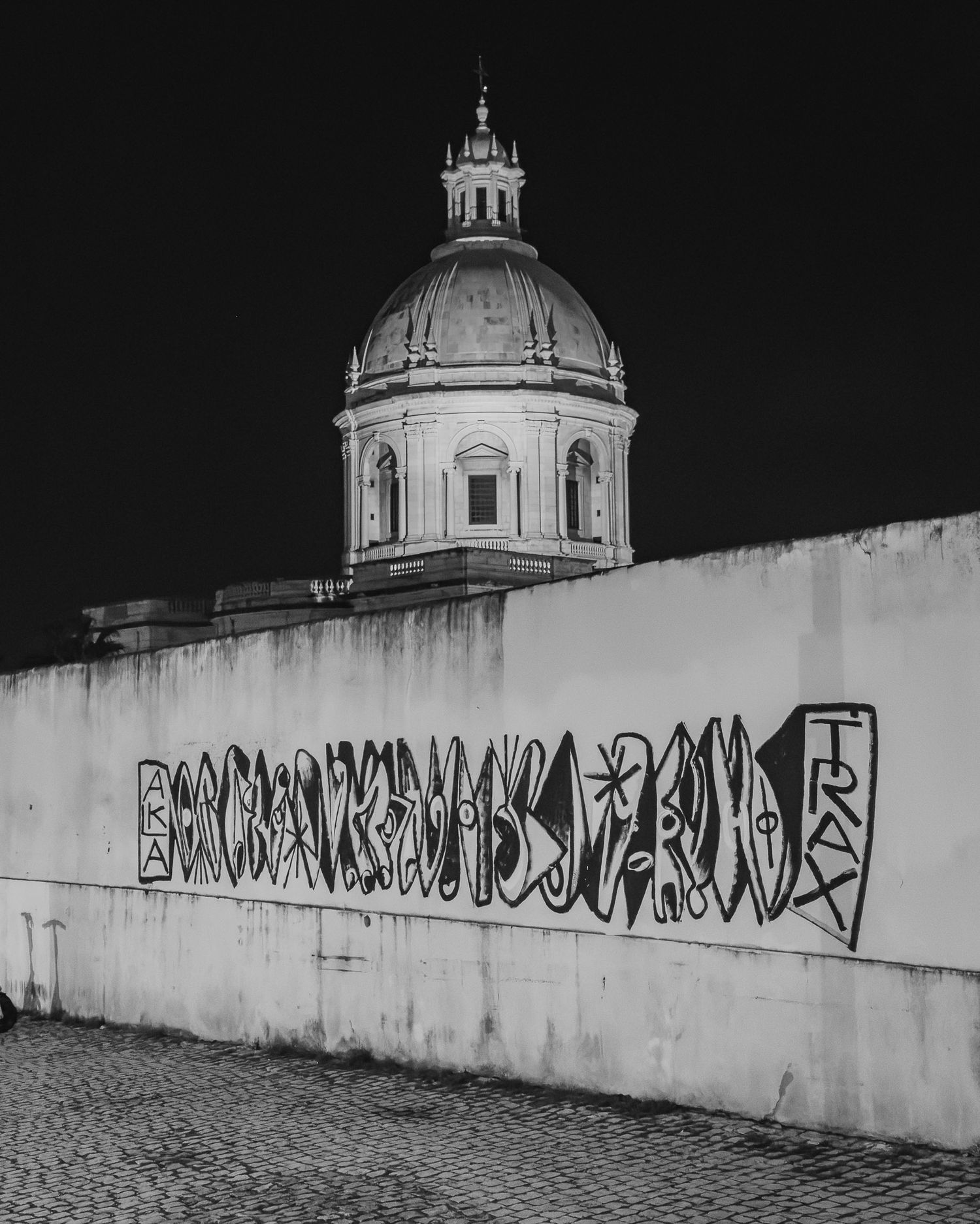 Domed church building with graffiti wall in dramatic black and white urban photography.