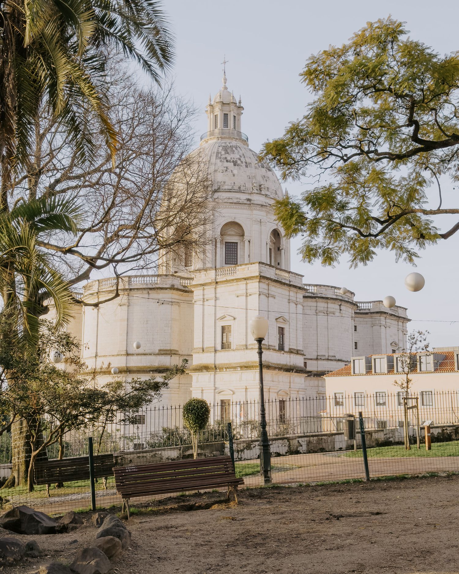 White domed church building surrounded by palm trees and park benches.