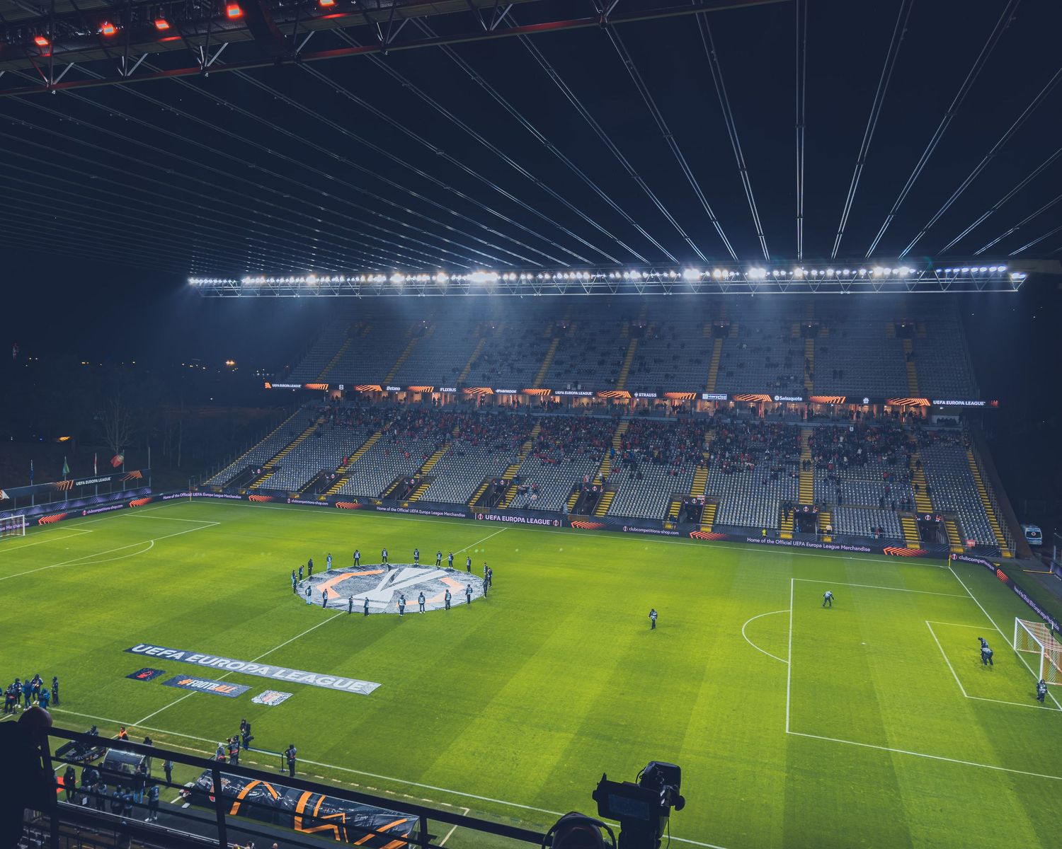 Illuminated soccer stadium at night with bright lights and empty field.