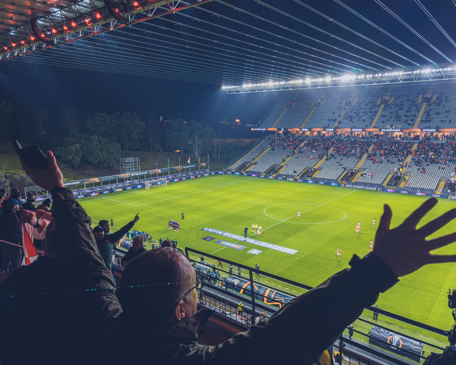 Soccer stadium filled with spectators and dramatic lighting during a nighttime match.