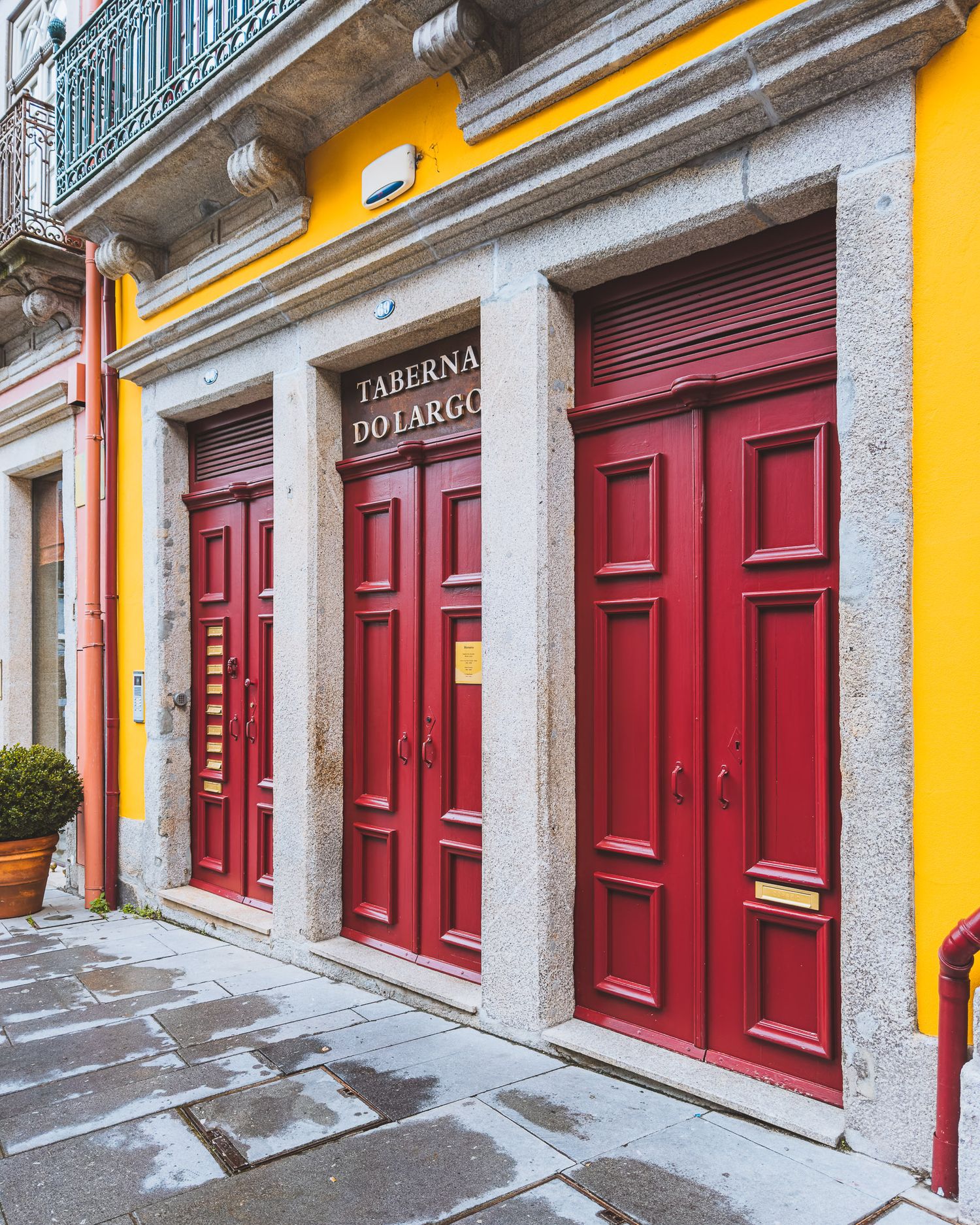 Row of bright red doors and yellow walls along a traditional European building facade.