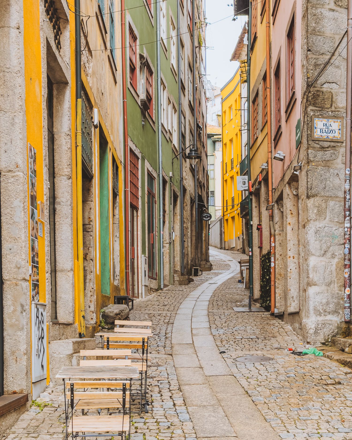 Narrow cobblestone street with colorful yellow and green buildings in an old European town.
