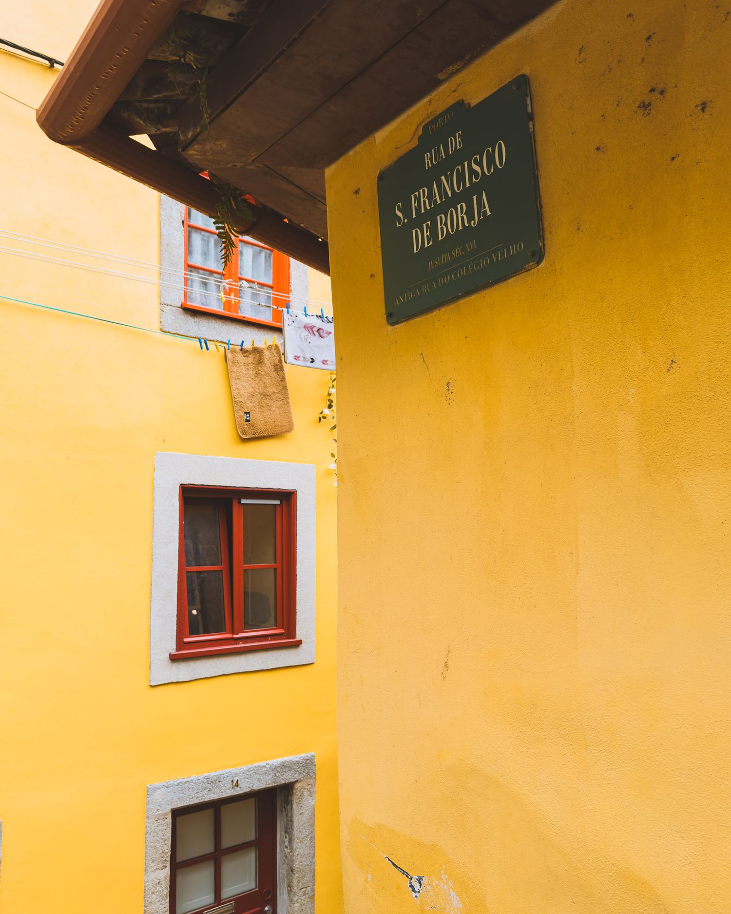 Yellow painted wall with rustic wooden doors and window frames in an old European alleyway.