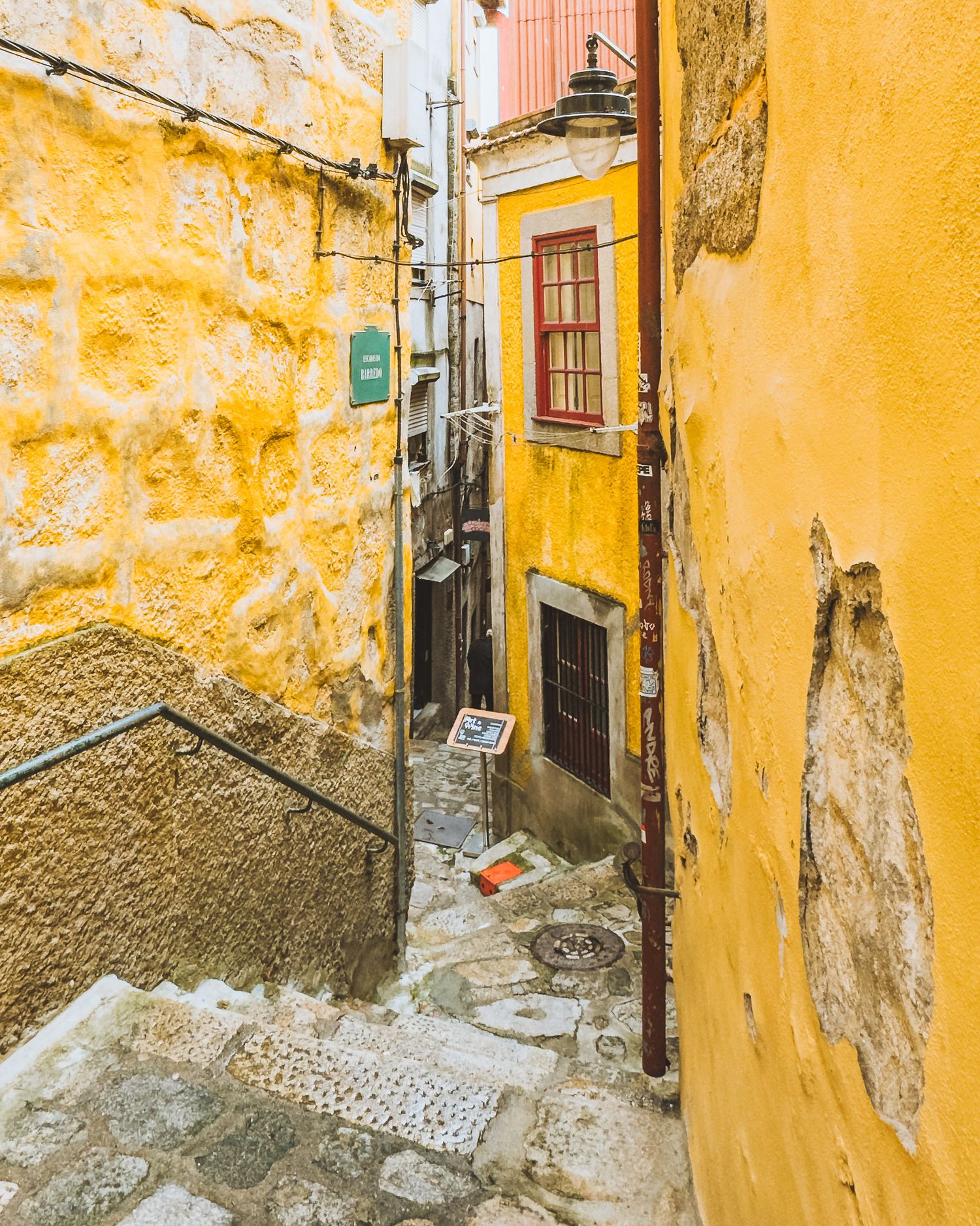 Narrow cobblestone alley with weathered yellow walls and traditional architecture.