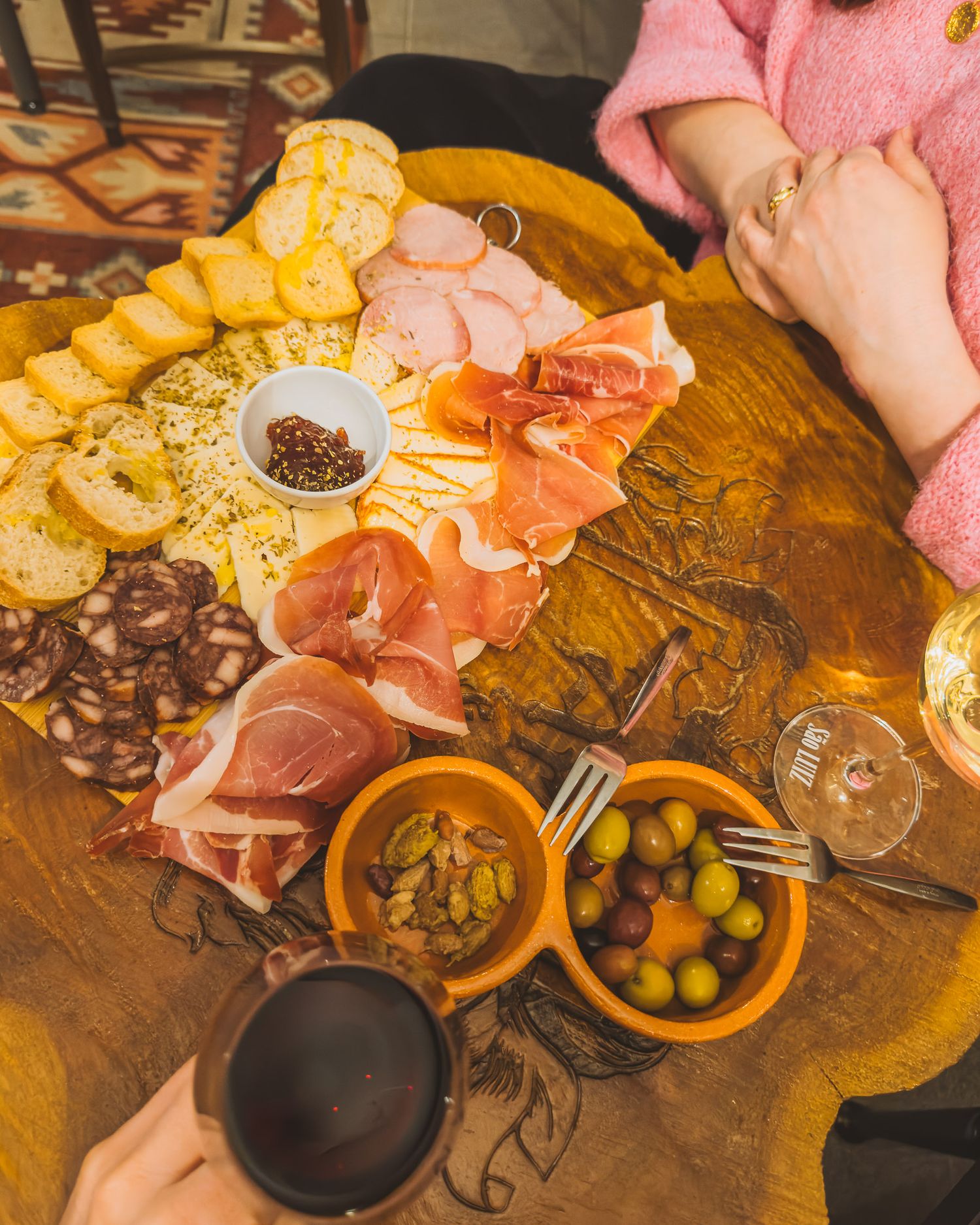 Rustic wooden table spread with charcuterie, olives, and appetizers for sharing.