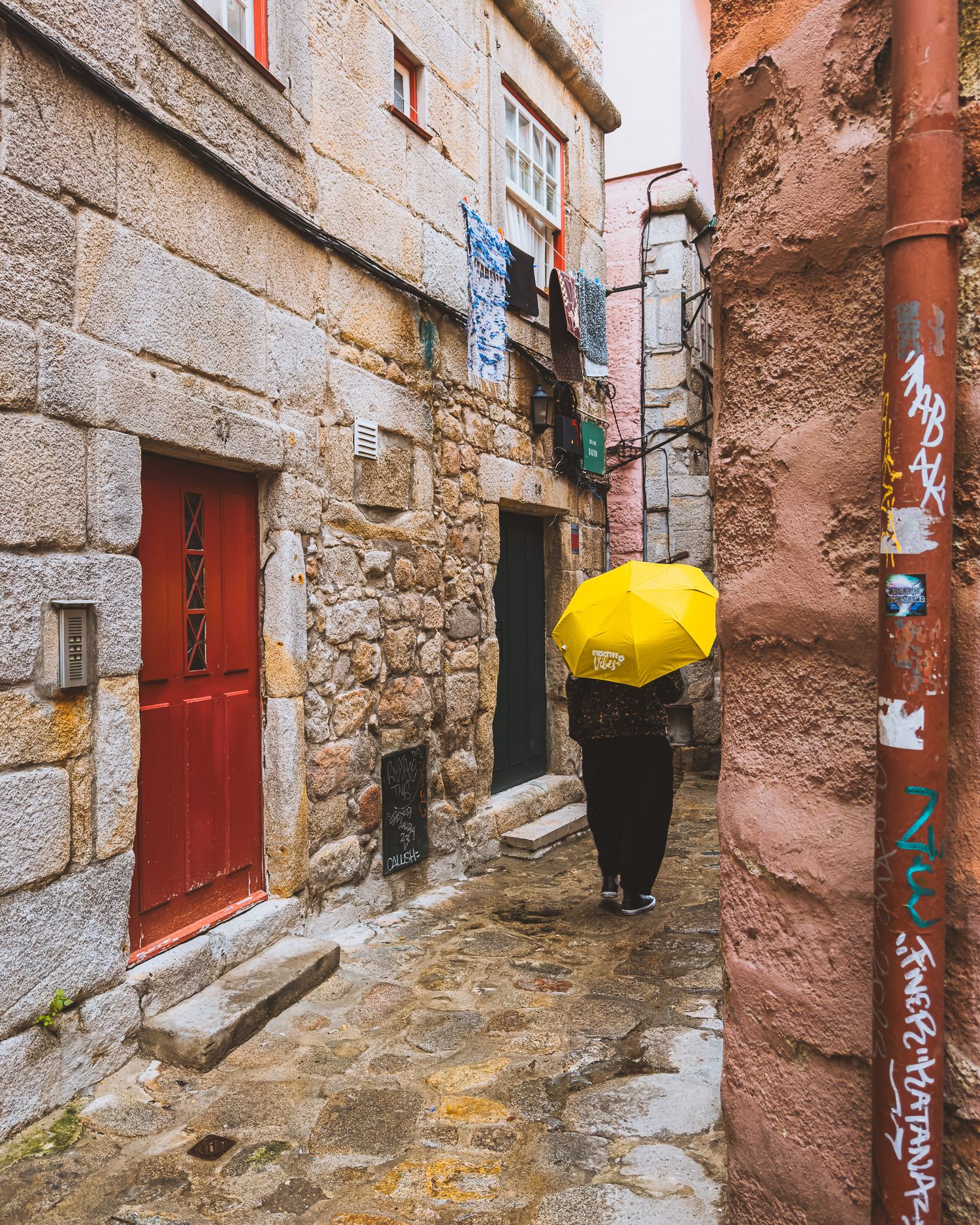 Historic stone alleyway with red doors and textured walls in a Mediterranean town.