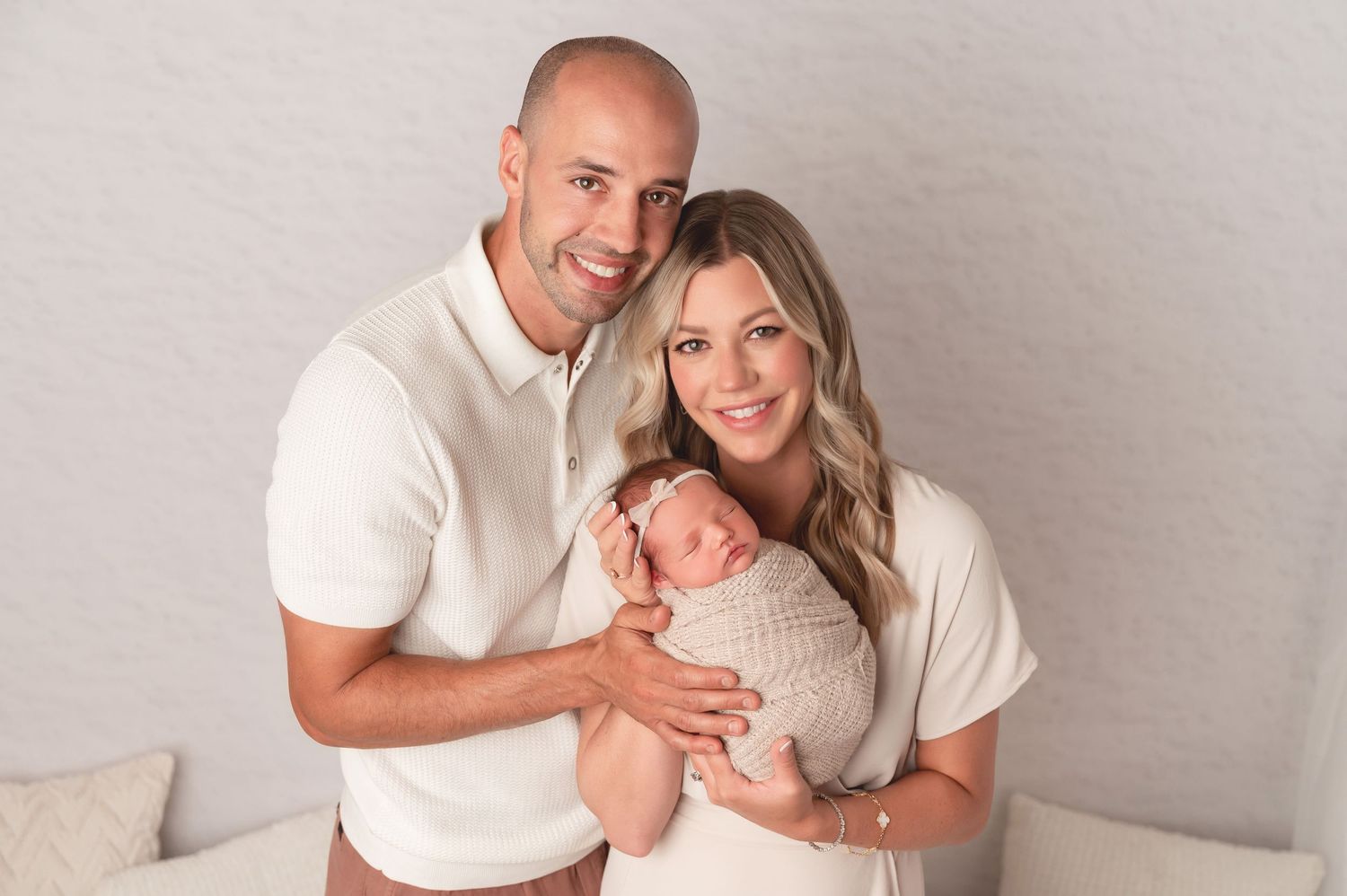 A couple in white outfits poses together for intimate portraits against a light gray background.