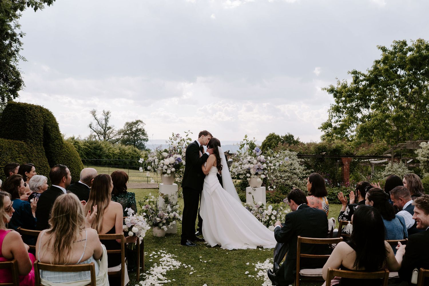 bride and groom share first kiss as husband and wife during wedding ceremony on lawn at dewsall court in herefordshire