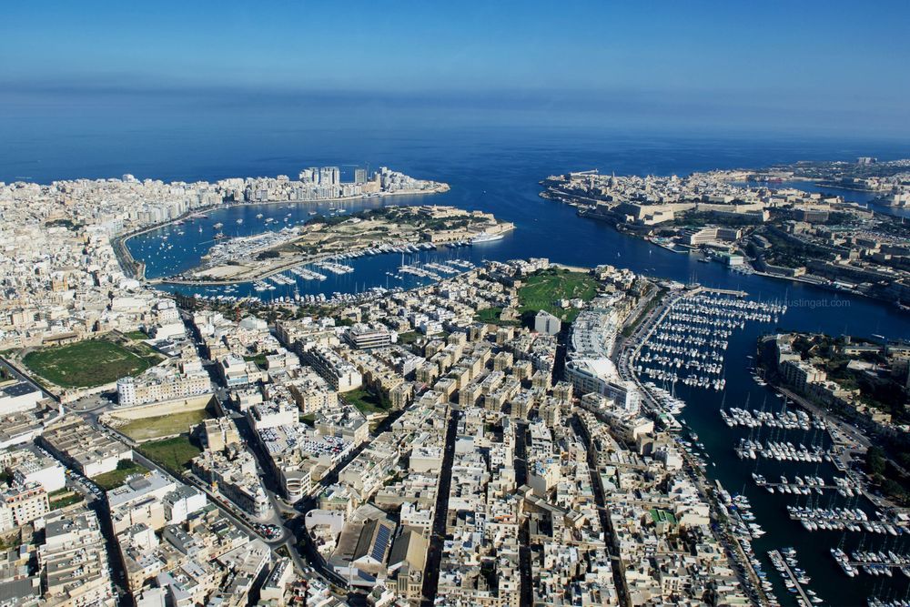 Overhead view of Malta's cityscape showing geometric street patterns and yacht-filled harbors.