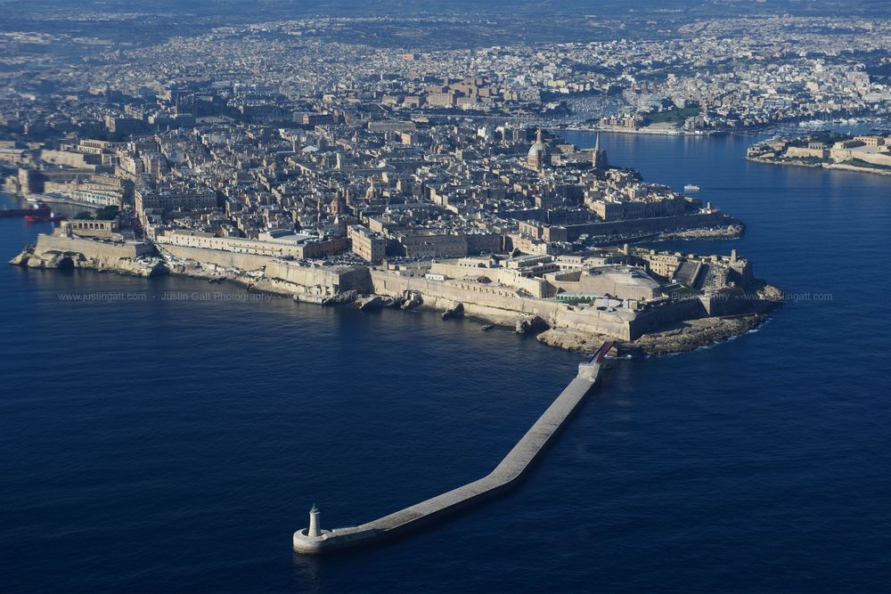 Aerial view of Malta's historic harbor with its distinctive breakwater extending into the Mediterranean Sea.